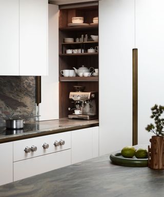 A white kitchen with a coffee station, a metal pot on the stove, and blue-green countertops and backsplash