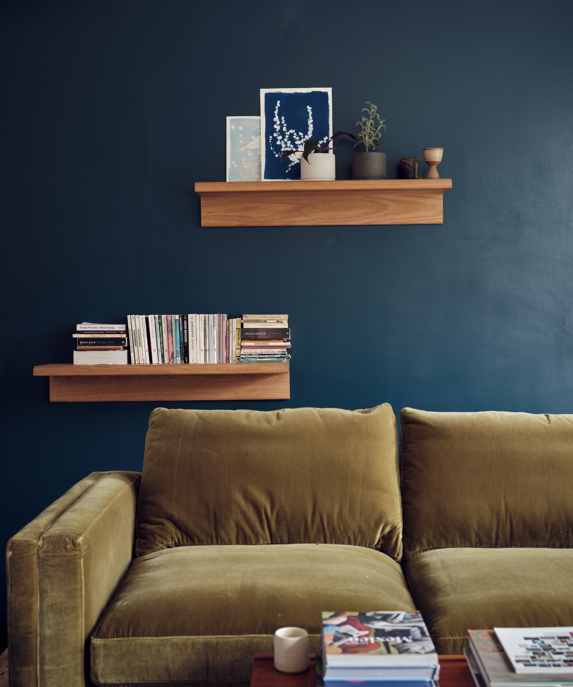 A living room painted in Farrow & Ball's Hague Blue with a golden-coloured velvet sofa