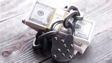 A couple of stacks of hundred-dollar bills are secured with a lock and chain.