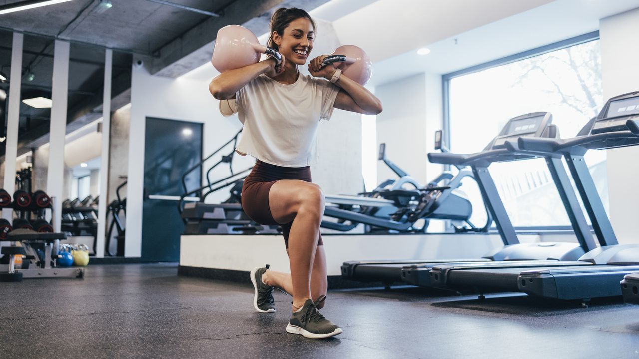 Woman working out with kettlebells in a gym