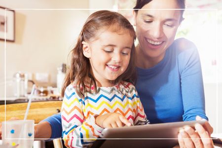 mother shows young child to use digital tablet