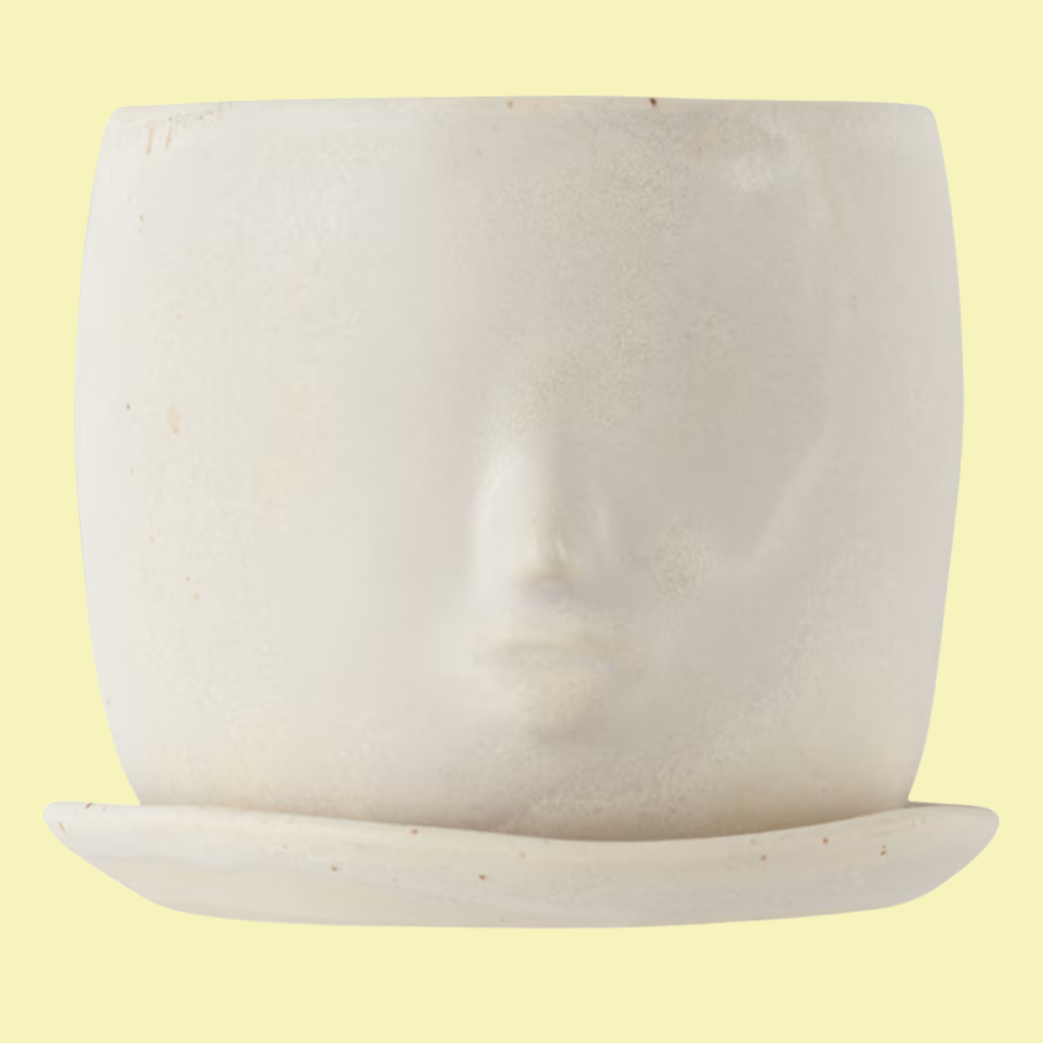 A sculpted face planter with a saucer