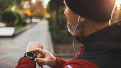 Man checks his fitness tracker while he exercises outdoors