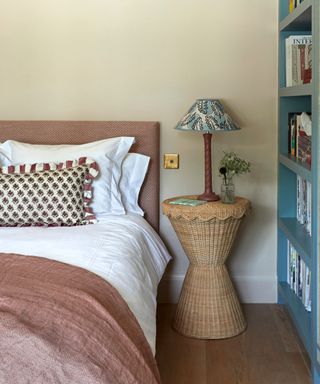 Close up of cozy bed with cream, pink and orange bedding, leaf outlined cushions, patterned cushion