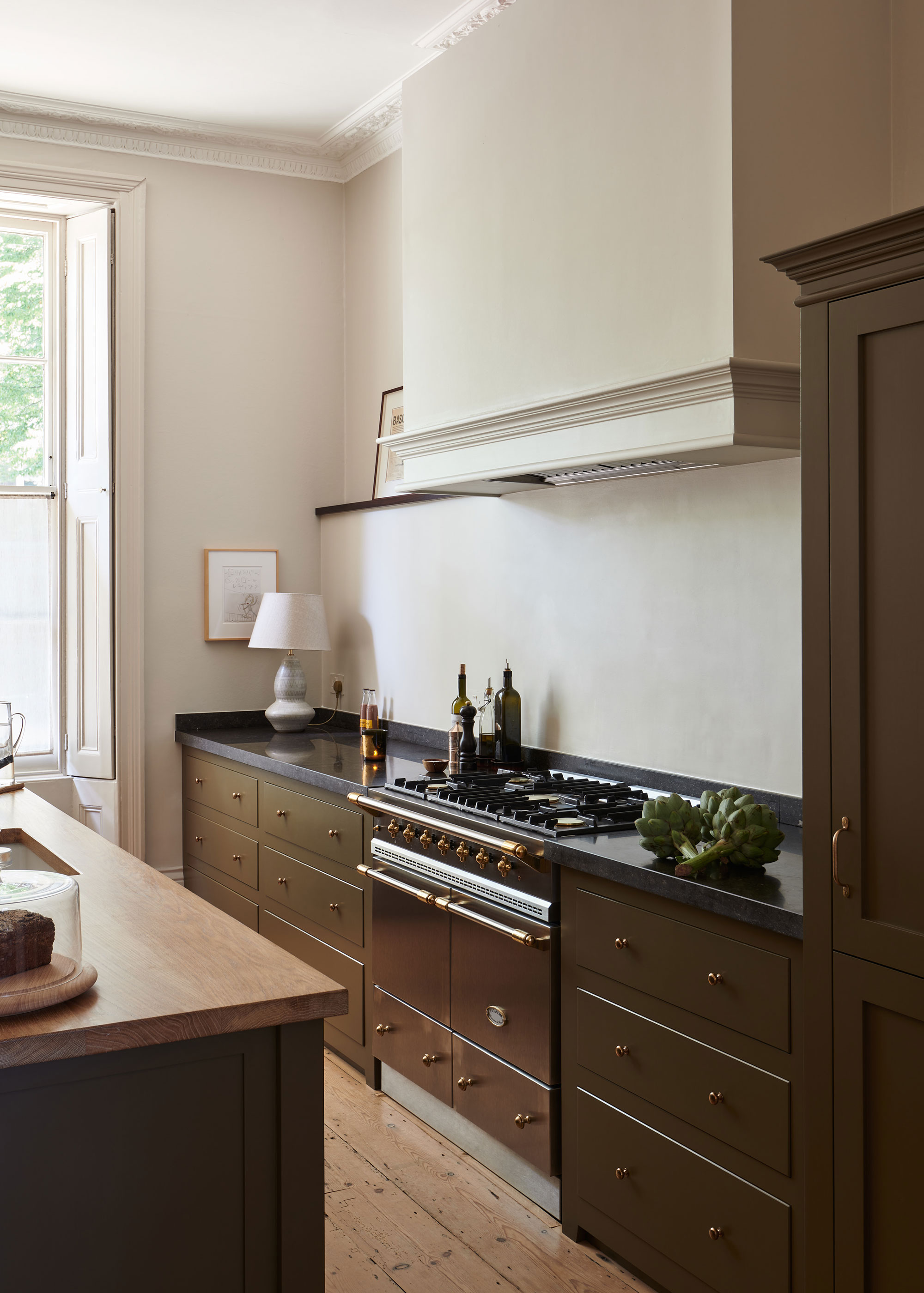 olive green kitchen with drawers and professional style range cooker with black work surfaces
