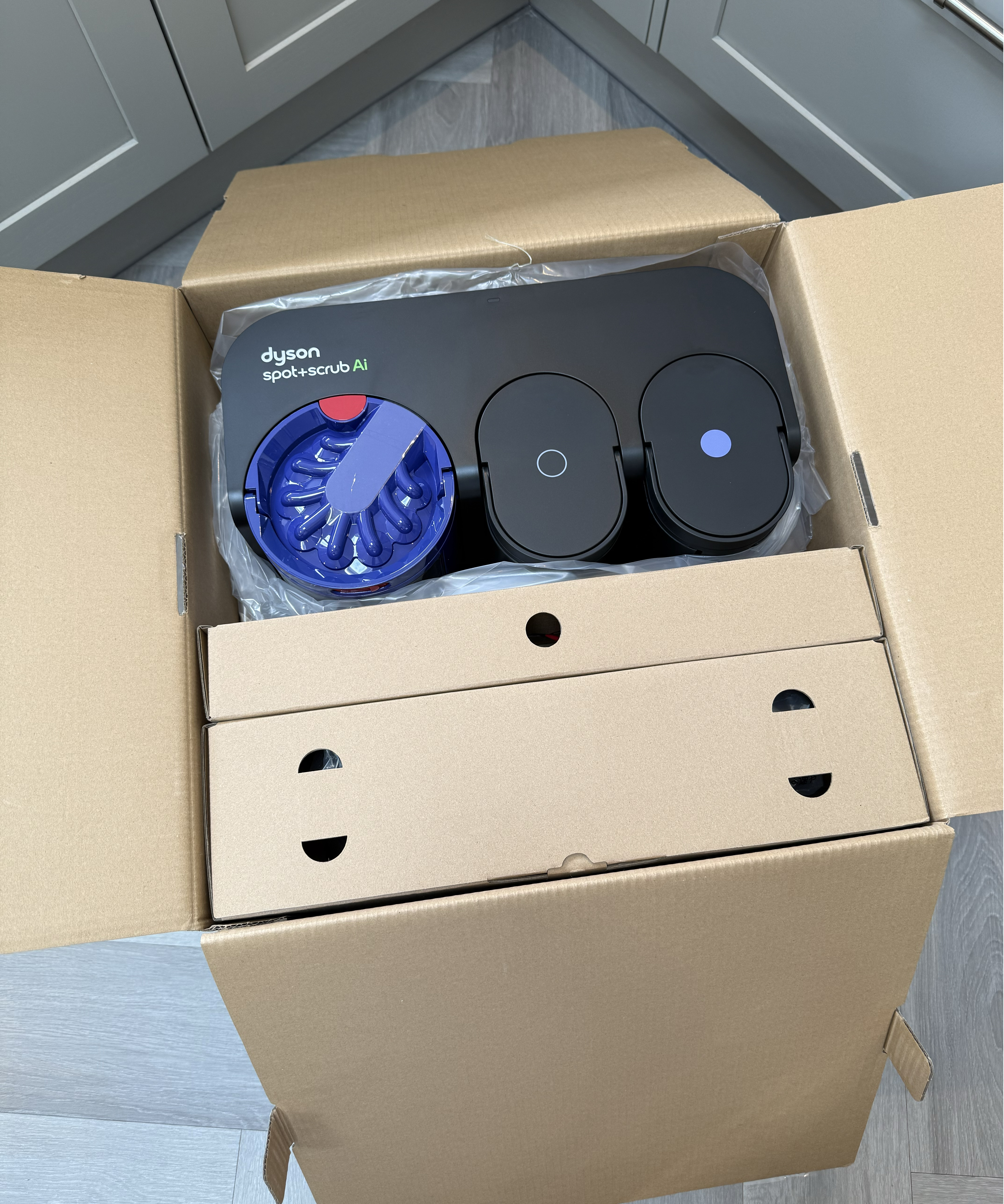 Dyson Spot+Scrub Ai dock and accessories packed inside an open cardboard box