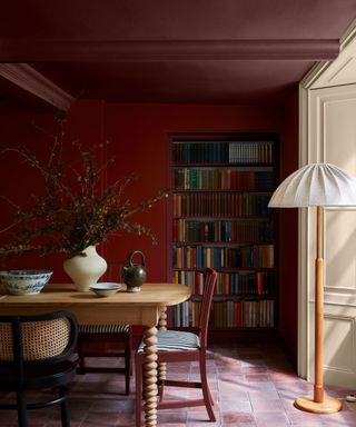 double drenched burgundy dining room with fitted bookcase and vintage furniture