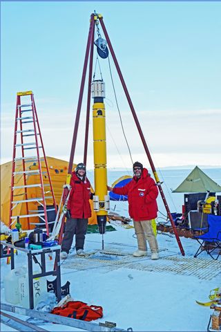 Two researchers stand next to Icefin before it goes on its underwater mission in Antarctica.