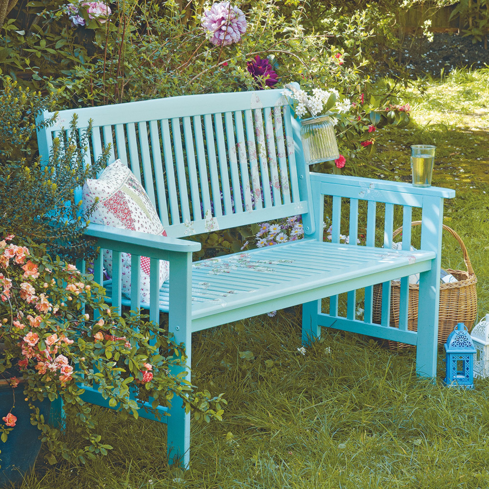 blue painted garden bench surrounded by flowers