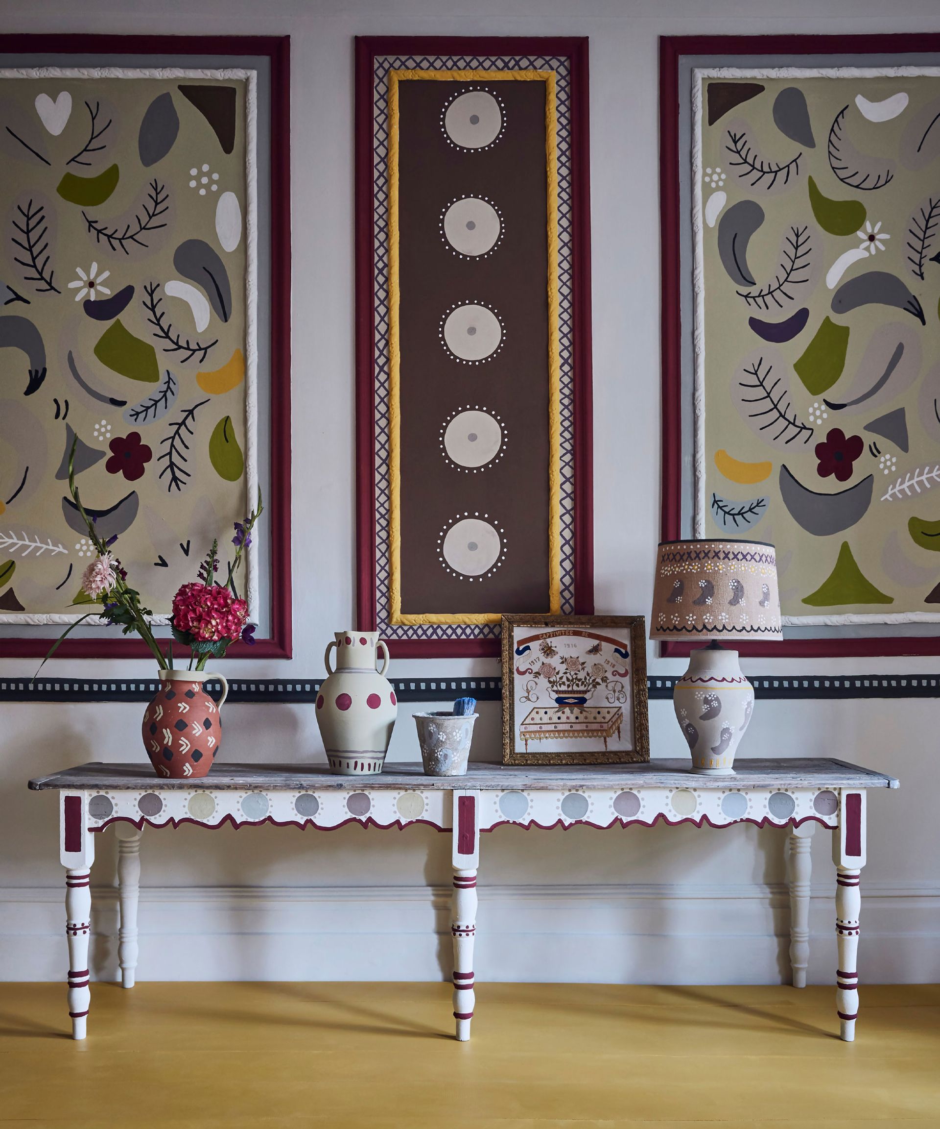 Bold, colorful entryway with painted walls and console table, decorated with ornaments and table lamp, paint from Annie Sloan