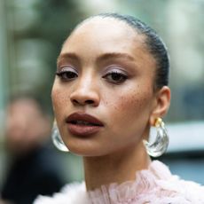a woman with visible freckles wearing watercolour flush make-up and perspex earrings