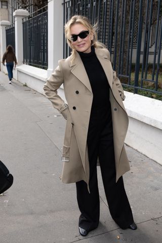 Renée Zellweger wearing a trench coat, black trousers, and a matching turtleneck.