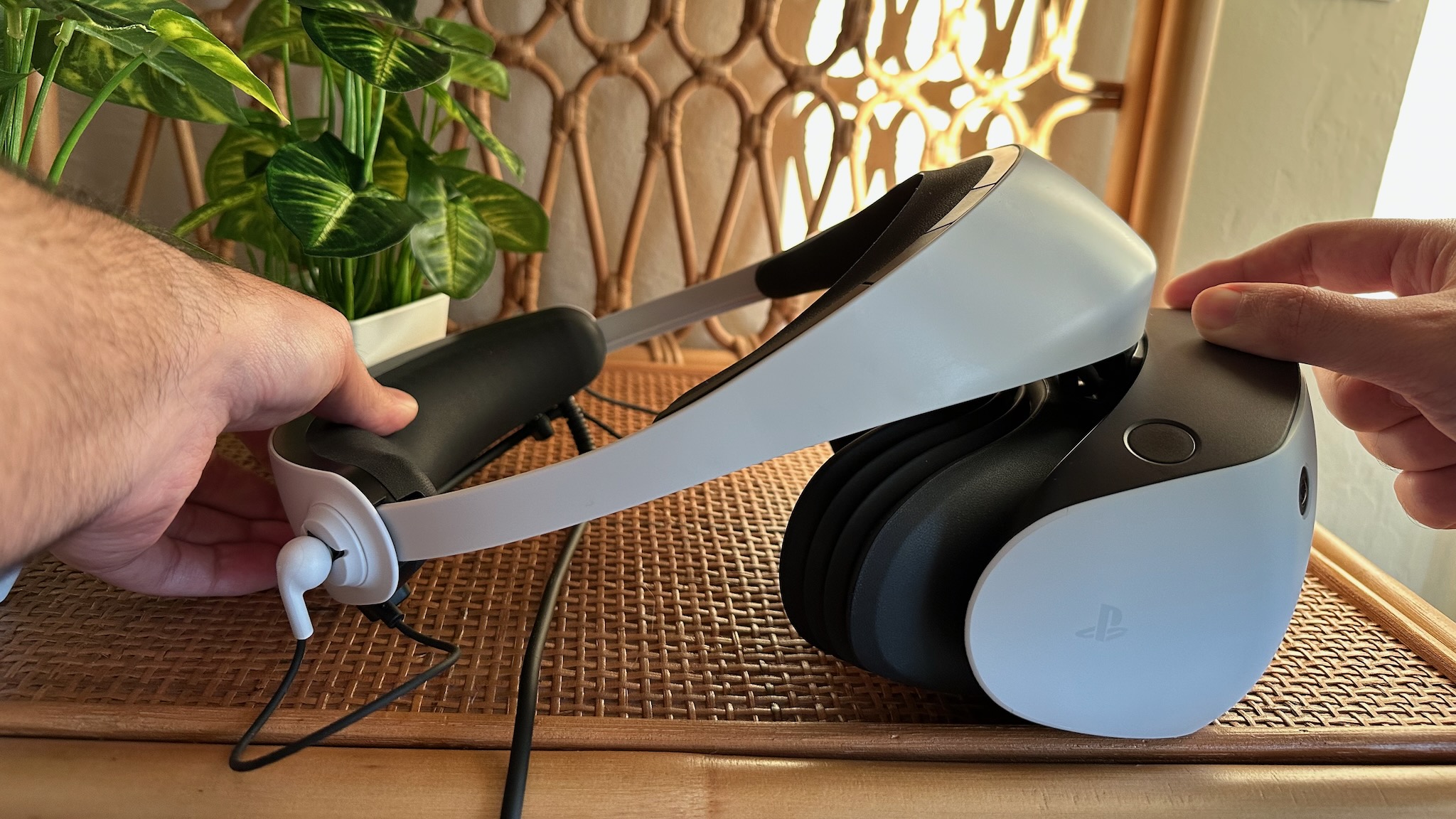 Sony PS VR2 with the head strap pulled open by two hands.