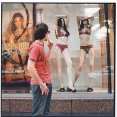 man looking at mannequins in lingerie in storefront window