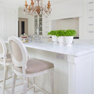 kitchen with white wall white chair chandelier and white counter