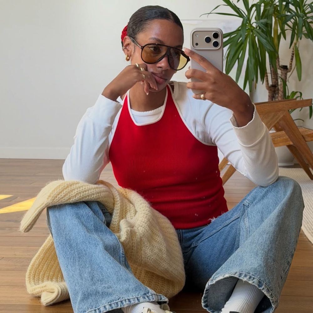 Influencer @claire_most wears a red vest top over a white tee with blue jeans and Nike X Jacquemus Moon Shoes