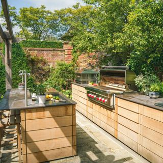 bespoke outdoor kitchen with cabinetry, BBQ, sink, kitchen island, stone floor