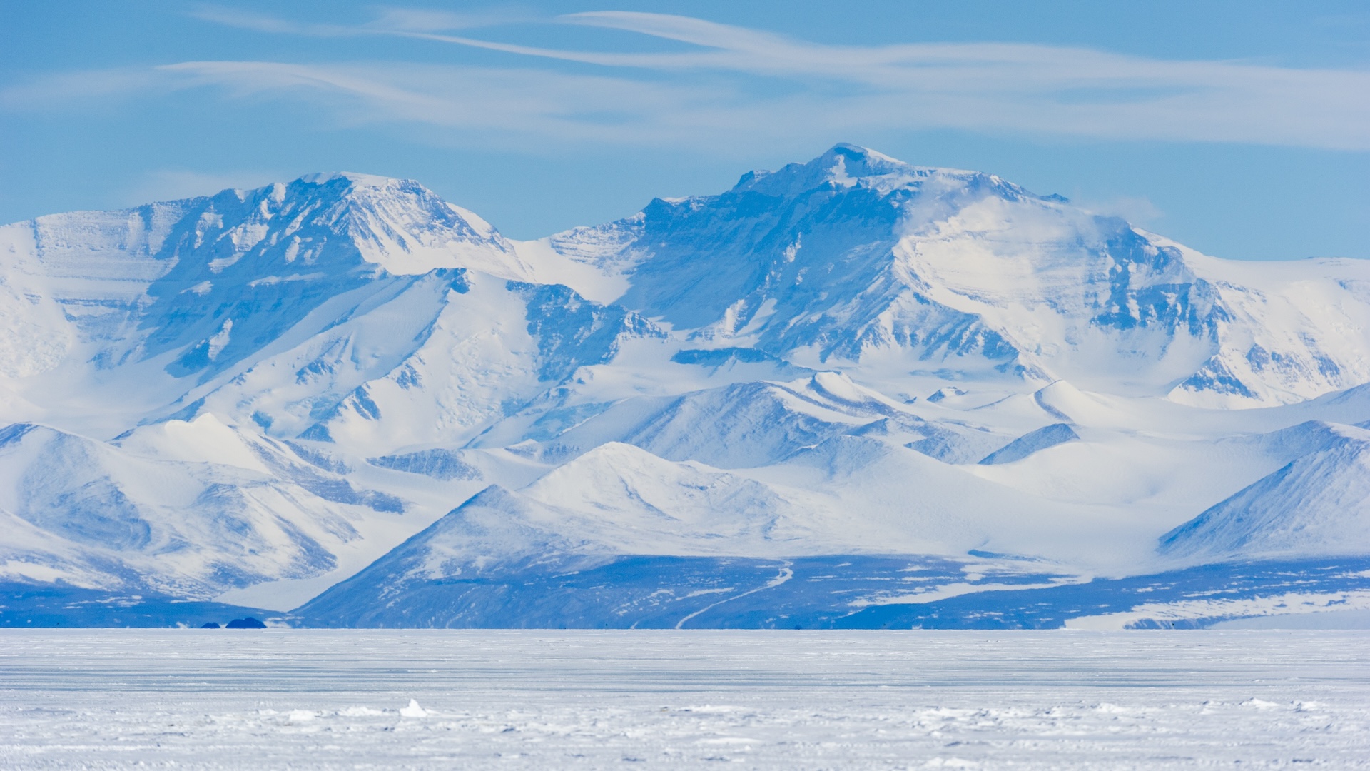 an icy mountain range rises from a flat plain