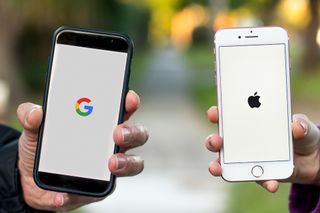 Hands holding smartphones with Google and Apple logos on the display