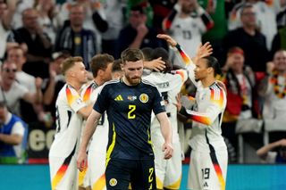 Scotland's Anthony Ralston looks dejected as Germany's players celebrate a goal in the opening game of Euro 2024 in Munich, Germany.