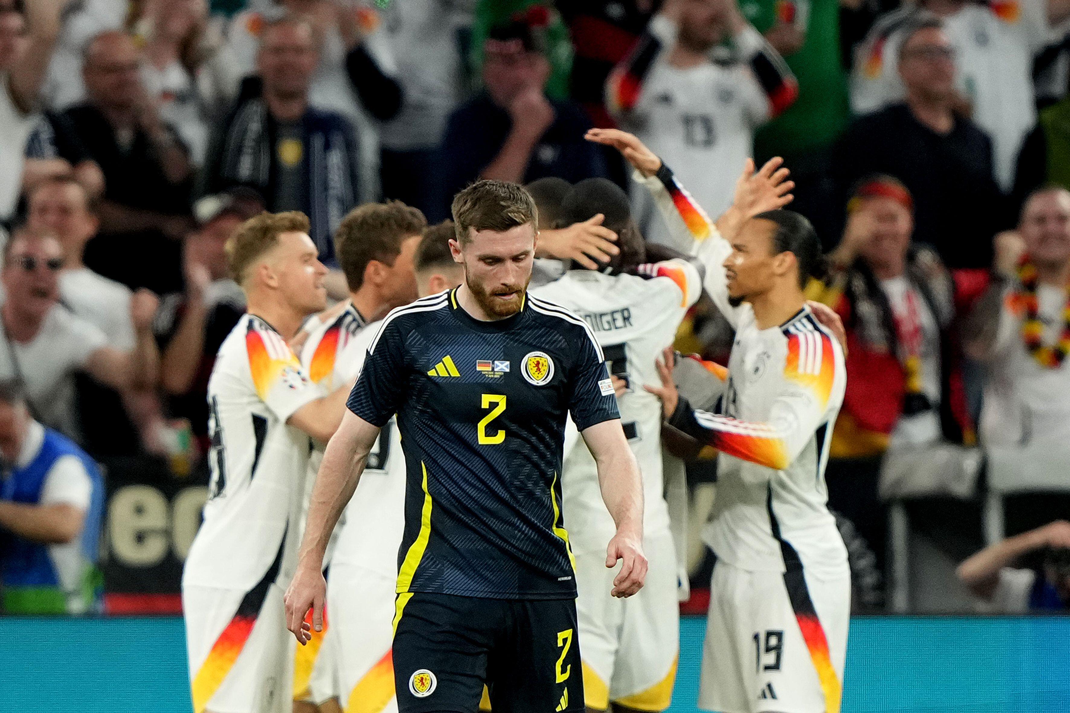 Scotland's Anthony Ralston looks dejected as Germany's players celebrate a goal in the opening game of Euro 2024 in Munich, Germany.