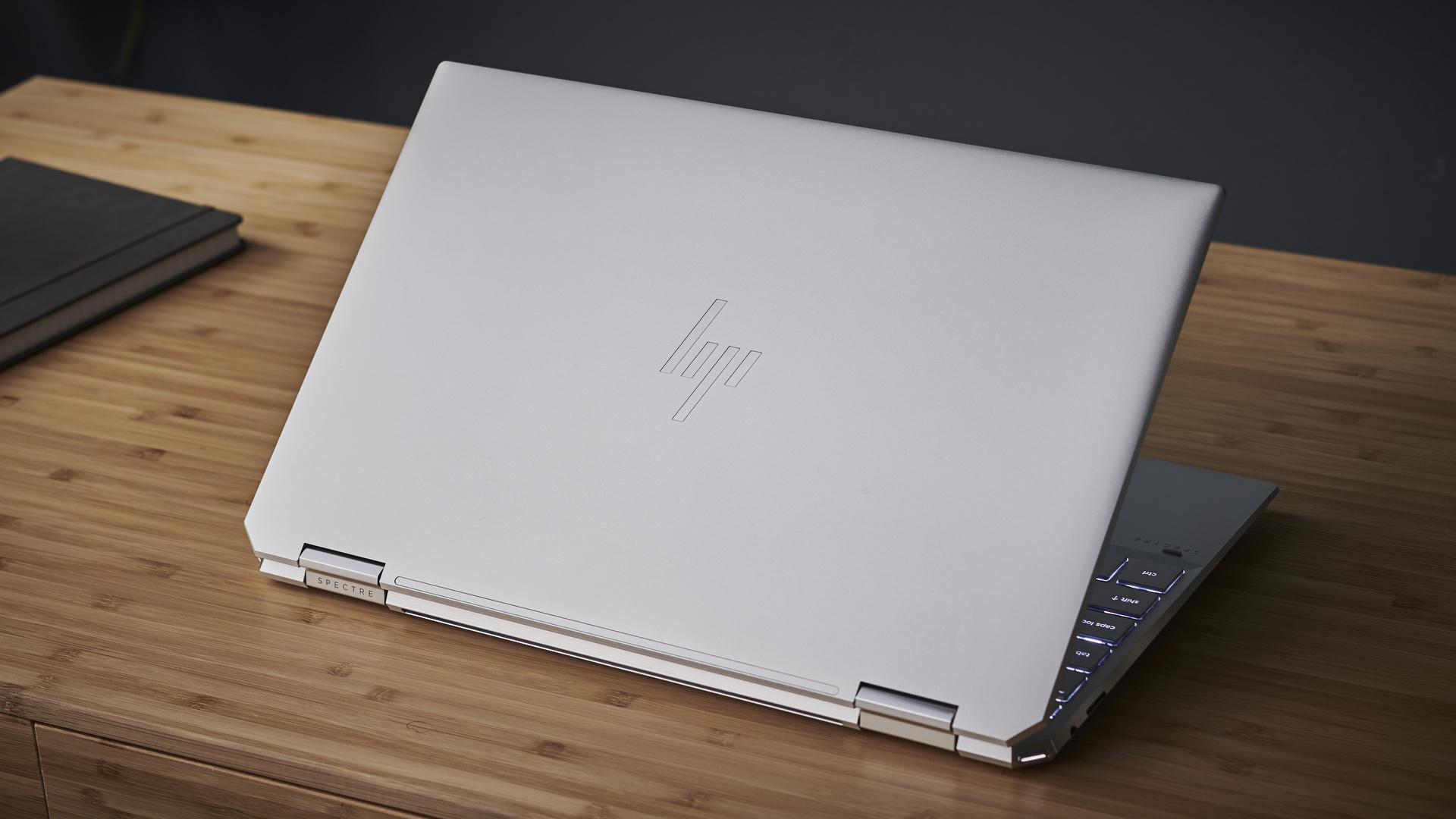 HP Spectre x360 (2021) on a wooden desk next to a notebook