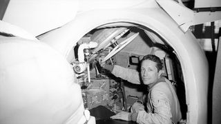 black and white photo of a man inside a mock space capsule