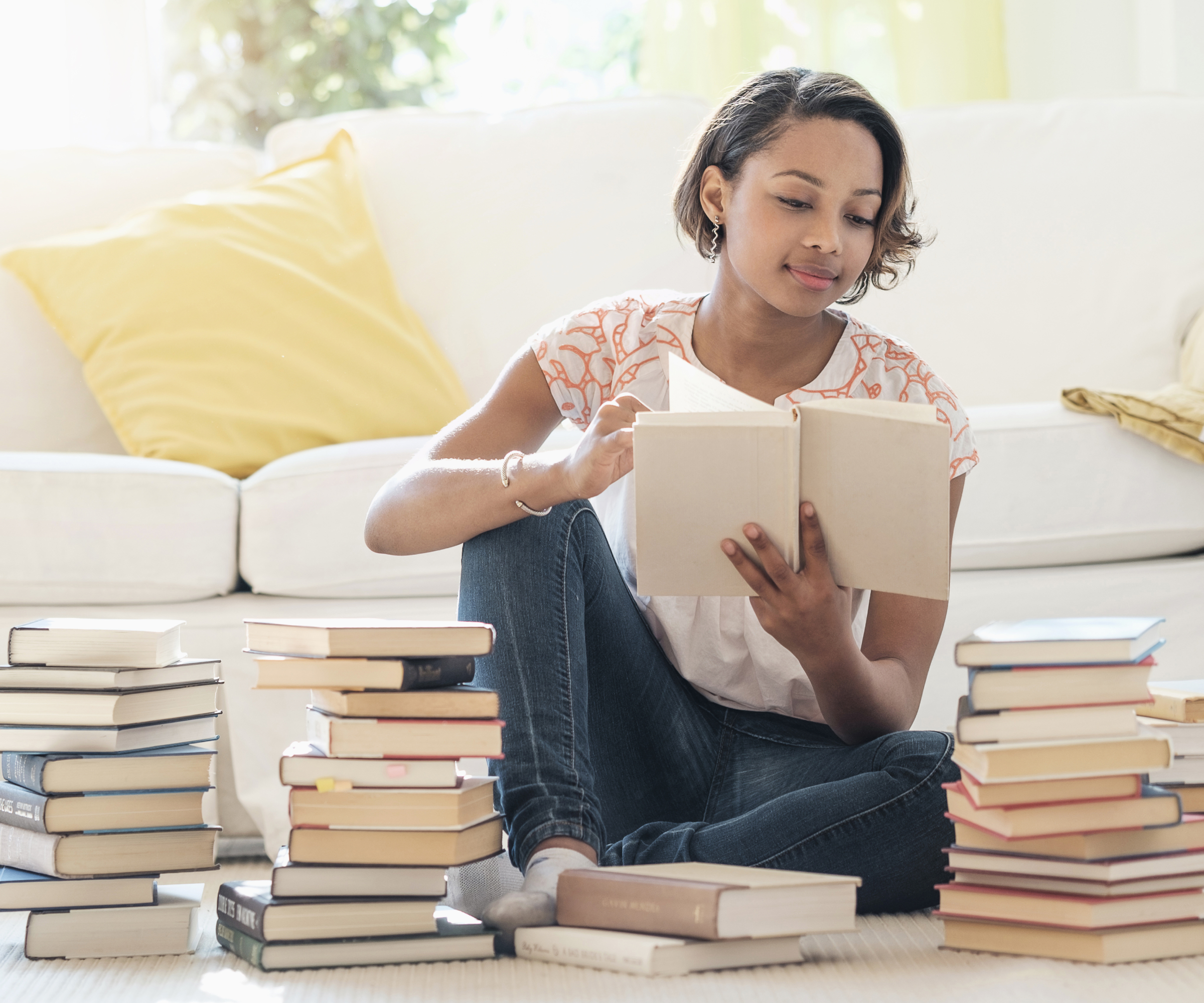 woman sat on floor looking through piles of books