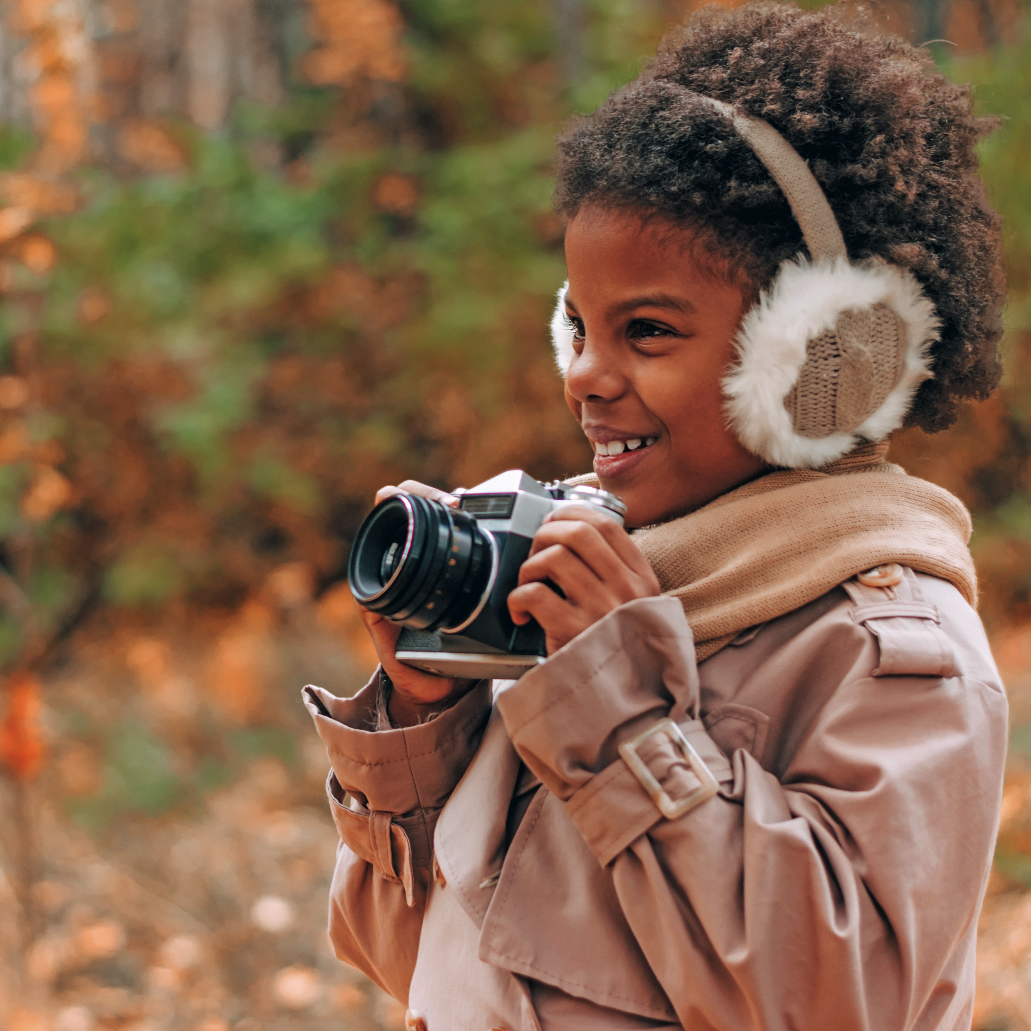 Child holding a camera in a forest on an autumn day