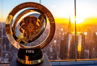 The FIFA Club World Cup trophy is displayed against a sunset backdrop, symbolizing the global vision for football as outlined in FourFourTwo's guide to the tournament.