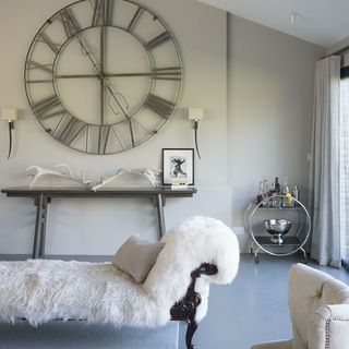 room with white wall and wall clock and faux fur bench seat