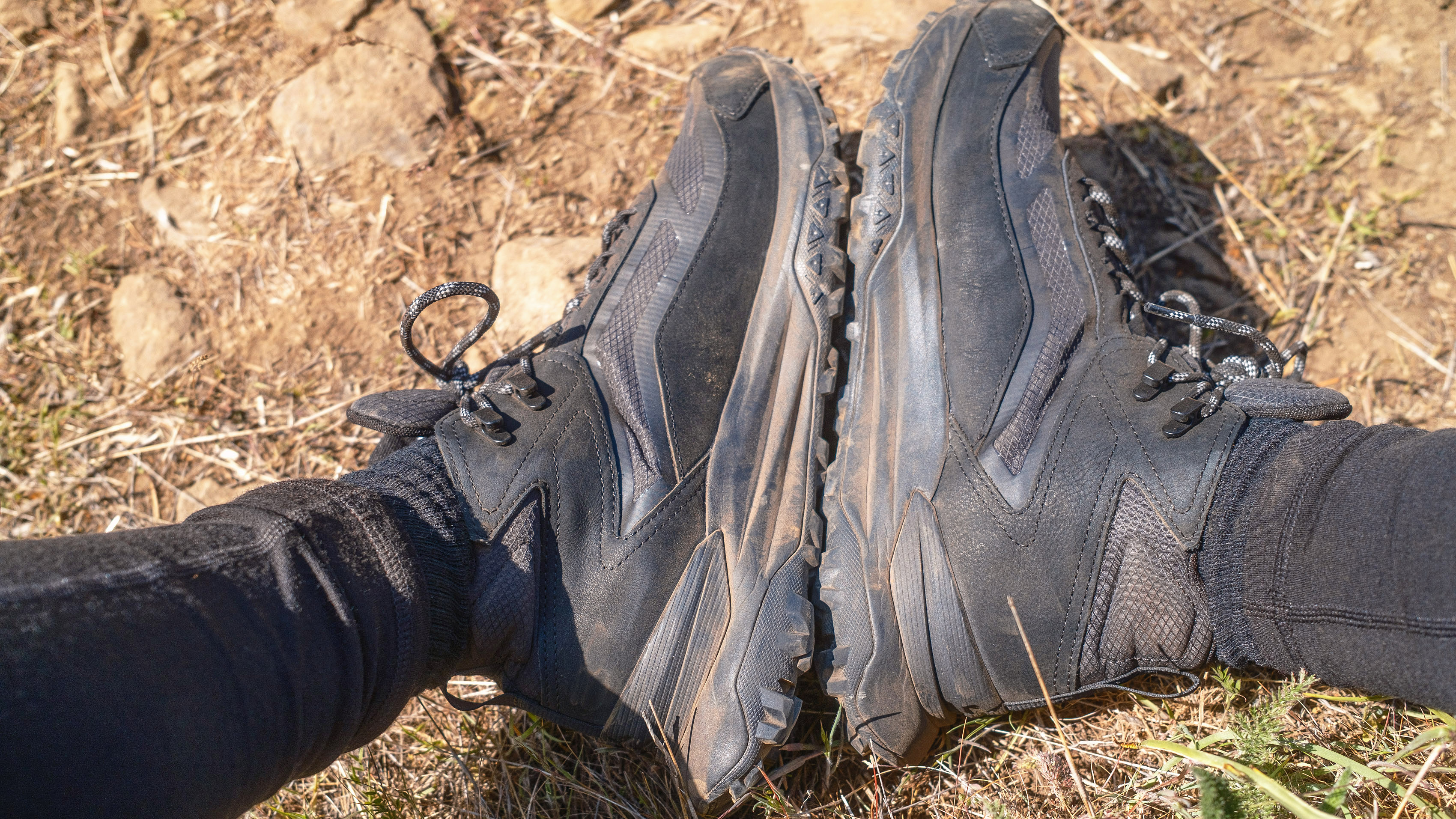 The Timberland Motion Access Mid Waterproof Sneakers (shown in black) on a hiker's feet shown with the soles pressed together
