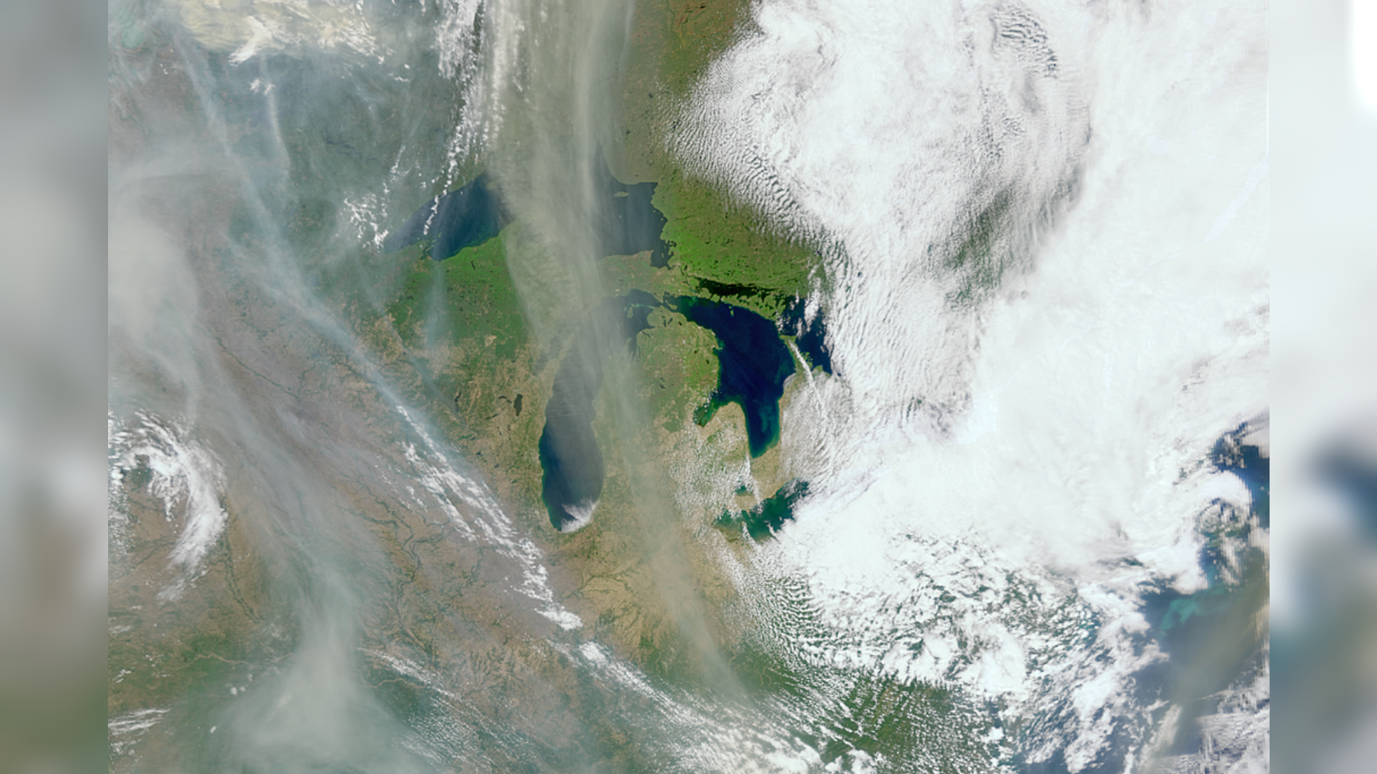 White and gray smoke hovers over an Earth landscape. 