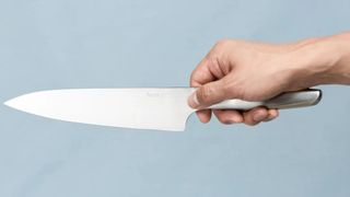 A man holds a stainless steel Hast chef's knife