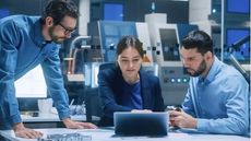 Colleagues in a tech lab all looking at a laptop
