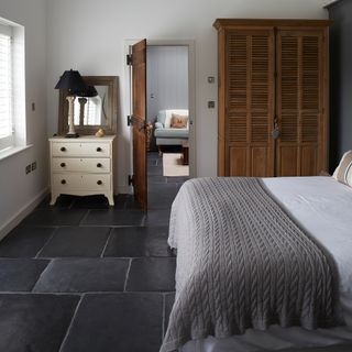 guest bedroom with wooden wardrobe and stone flooring
