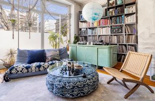 Eclectic living room with book shelf, sideboard, occasional chair, sofa, low hanging lantern