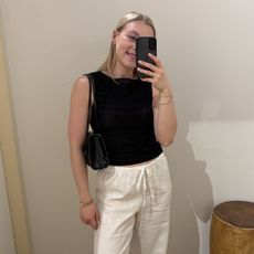Woman wearing striped waistcoat and white linen trousers