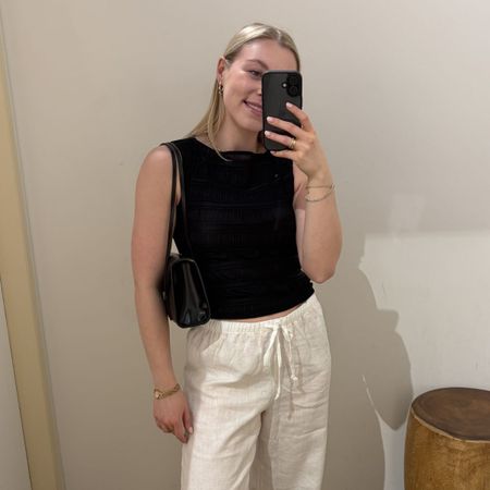 Woman wearing striped waistcoat and white linen trousers
