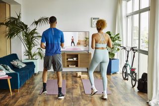 A couple working out in their home using an exercise video on their television.