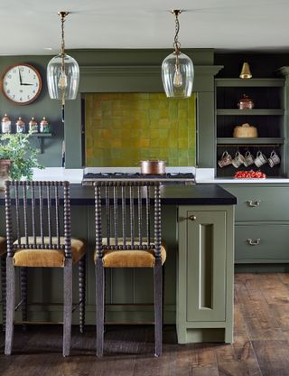 Kitchen with tiled backsplash, green cabinets and wood stools