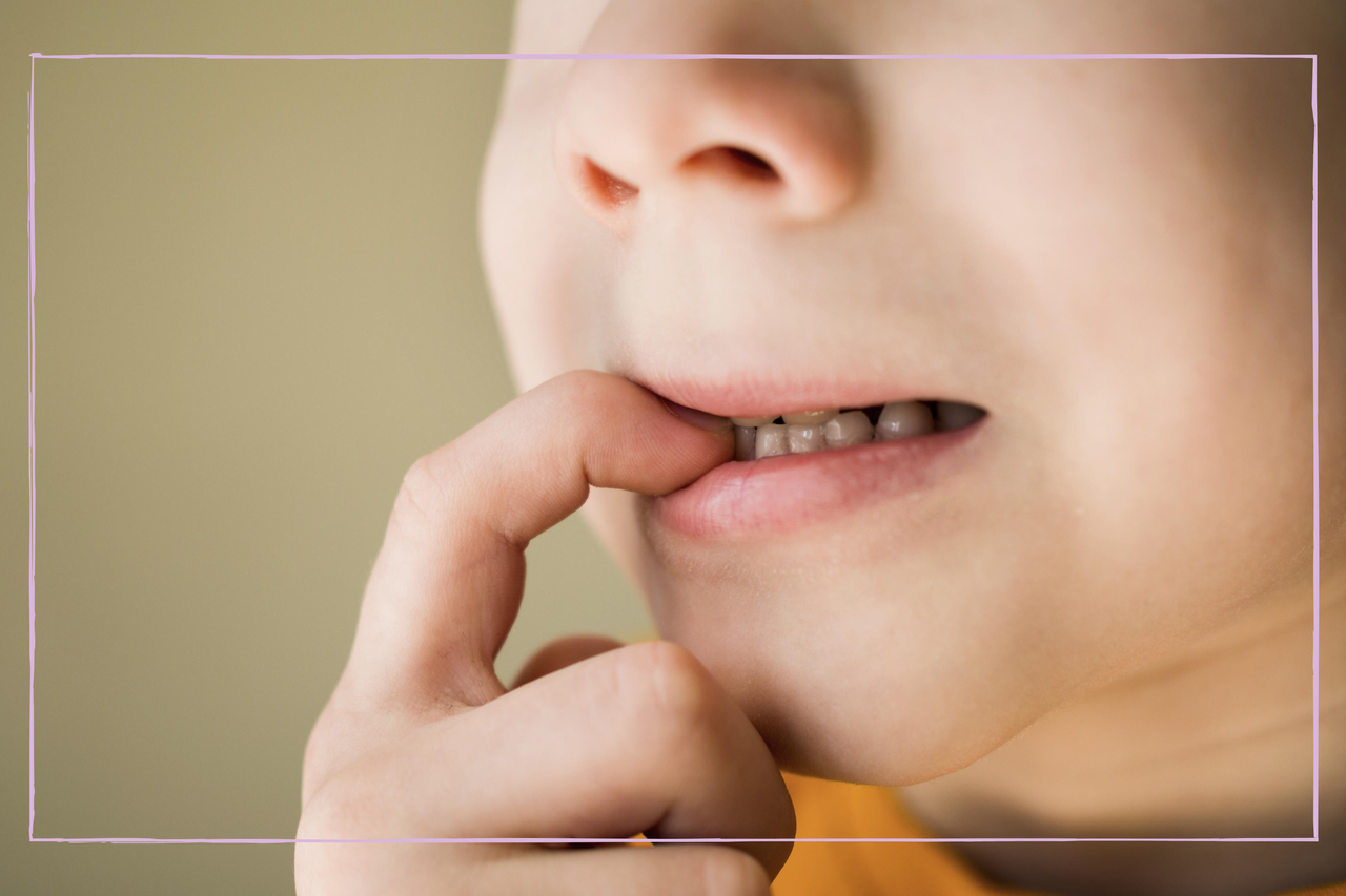 young boy biting fingernail