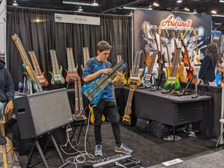 A guitarist demos an FM Guitars model at the company's NAMM 2022 booth