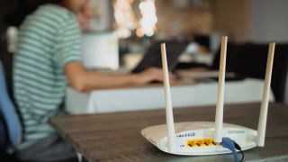 A woman is working at home using a modem router, connecting the Internet to her laptop.