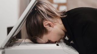 Person resting their head in despair on a printer