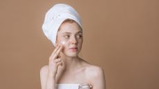 woman wearing a towel on her head applying skincare - what is slugging
