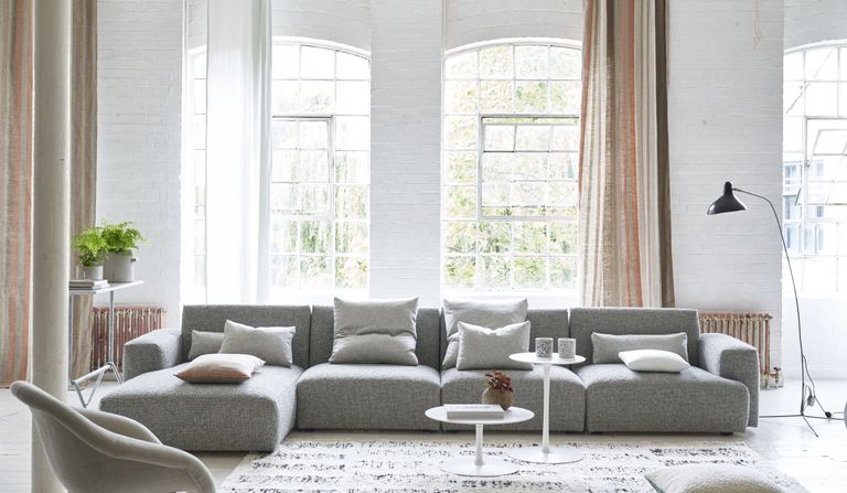Sectional living room ideas – white living room with gray sectional, console, side tables, rug, stripe drapes 