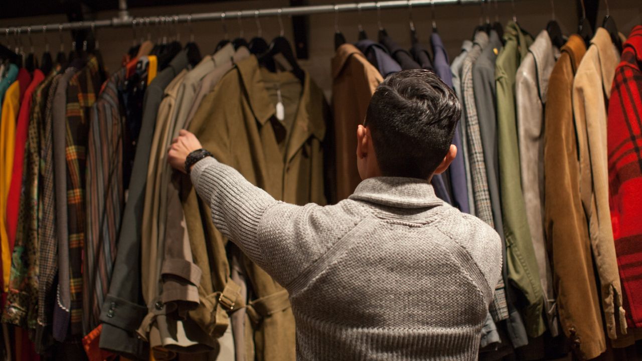 Young man looking through clothes rail in vintage shop