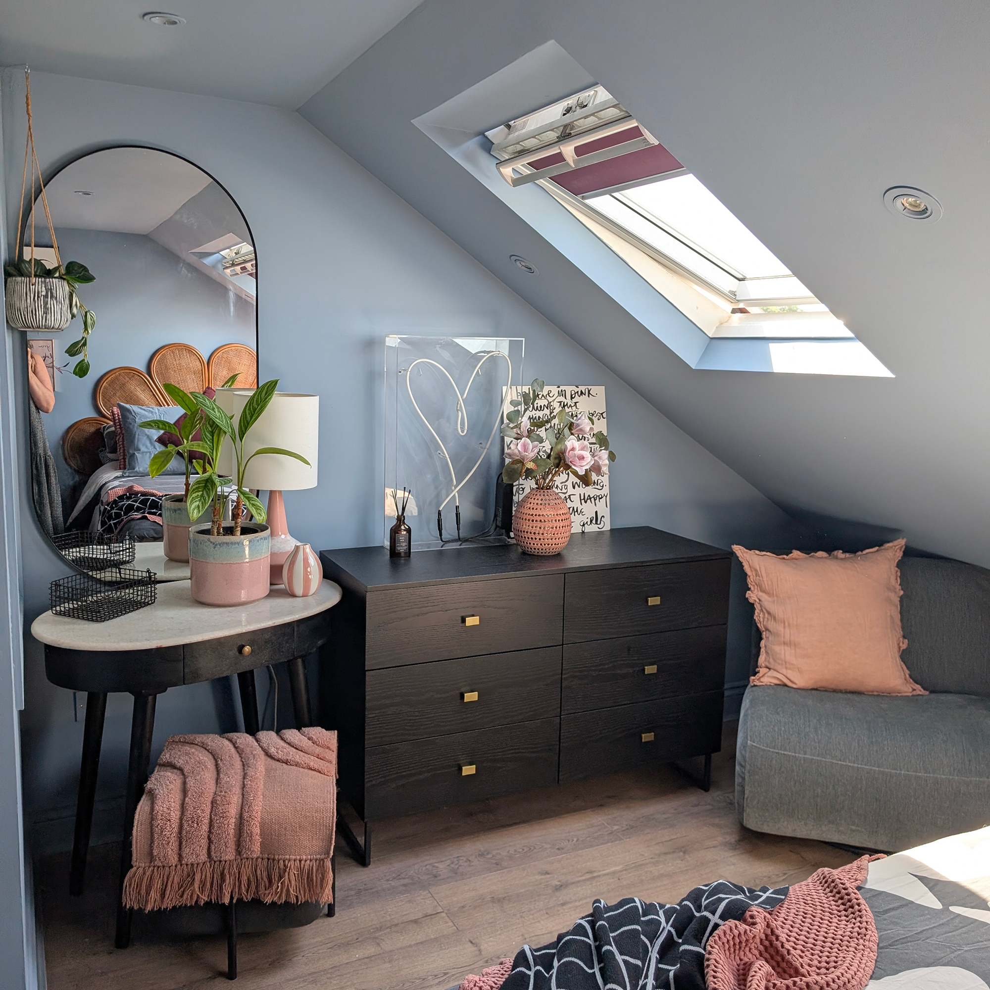 Blue eaves bedroom with skylight, wooden floor, dark wood furniture and oval mirror