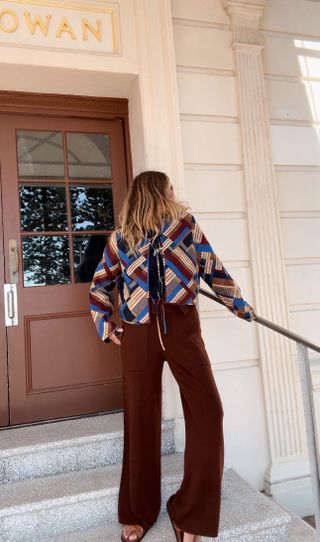 Woman wears brown trousers and patterned top